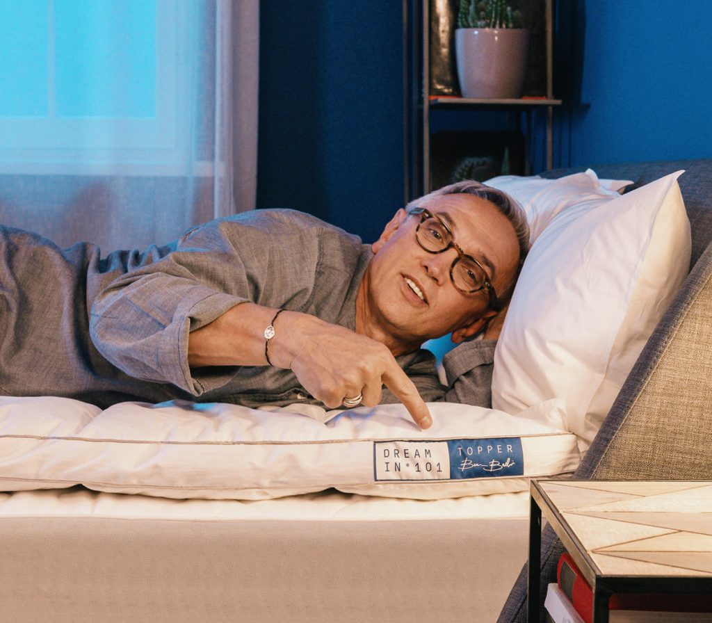 Topper Bruno Barbieri di Dreamin*101 sul materasso, con Bruno Barbieri sdraiato accanto