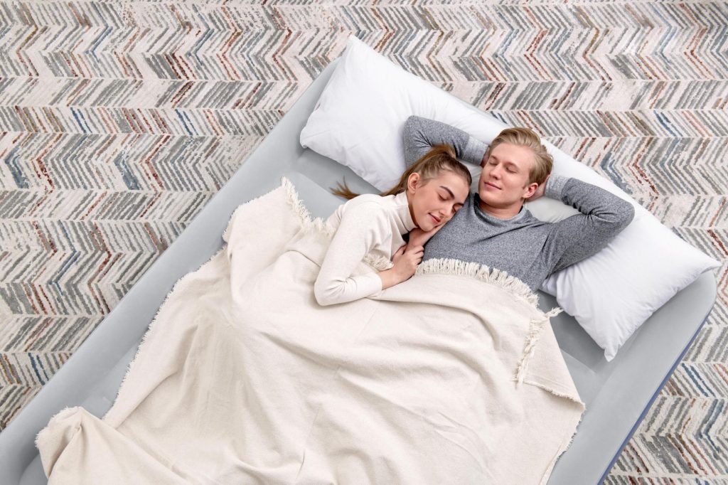 Una coppia sdraiata sul Bestway Tritech 6713I con cuscini e coperta