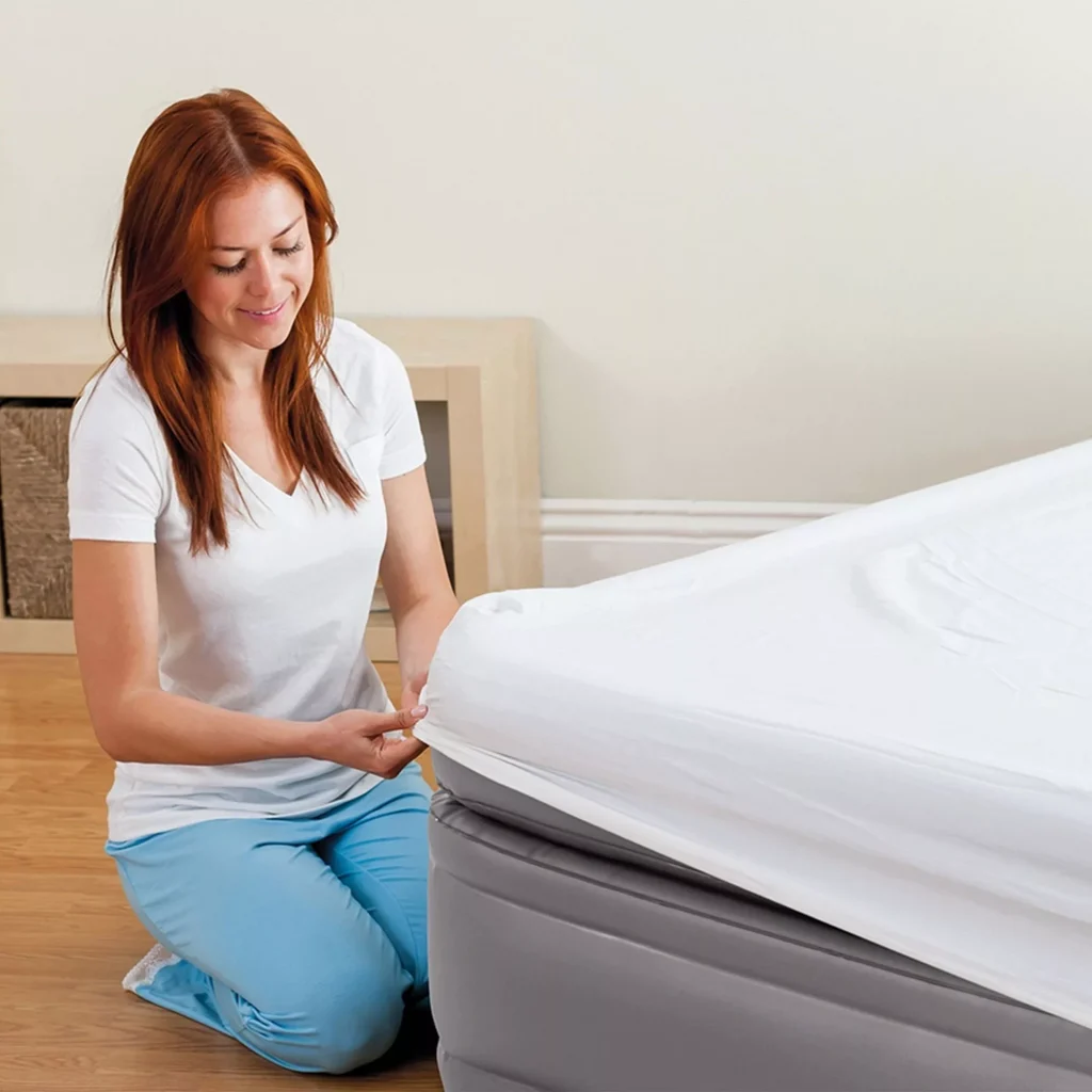 Una donna rimbocca il lenzuolo sull'Intex Dura-Beam Prime Comfort Elevated Singolo