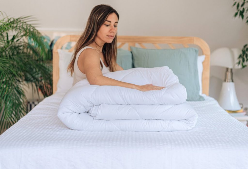 Donna che piega lo Slome Piumone 4 stagioni sul letto
